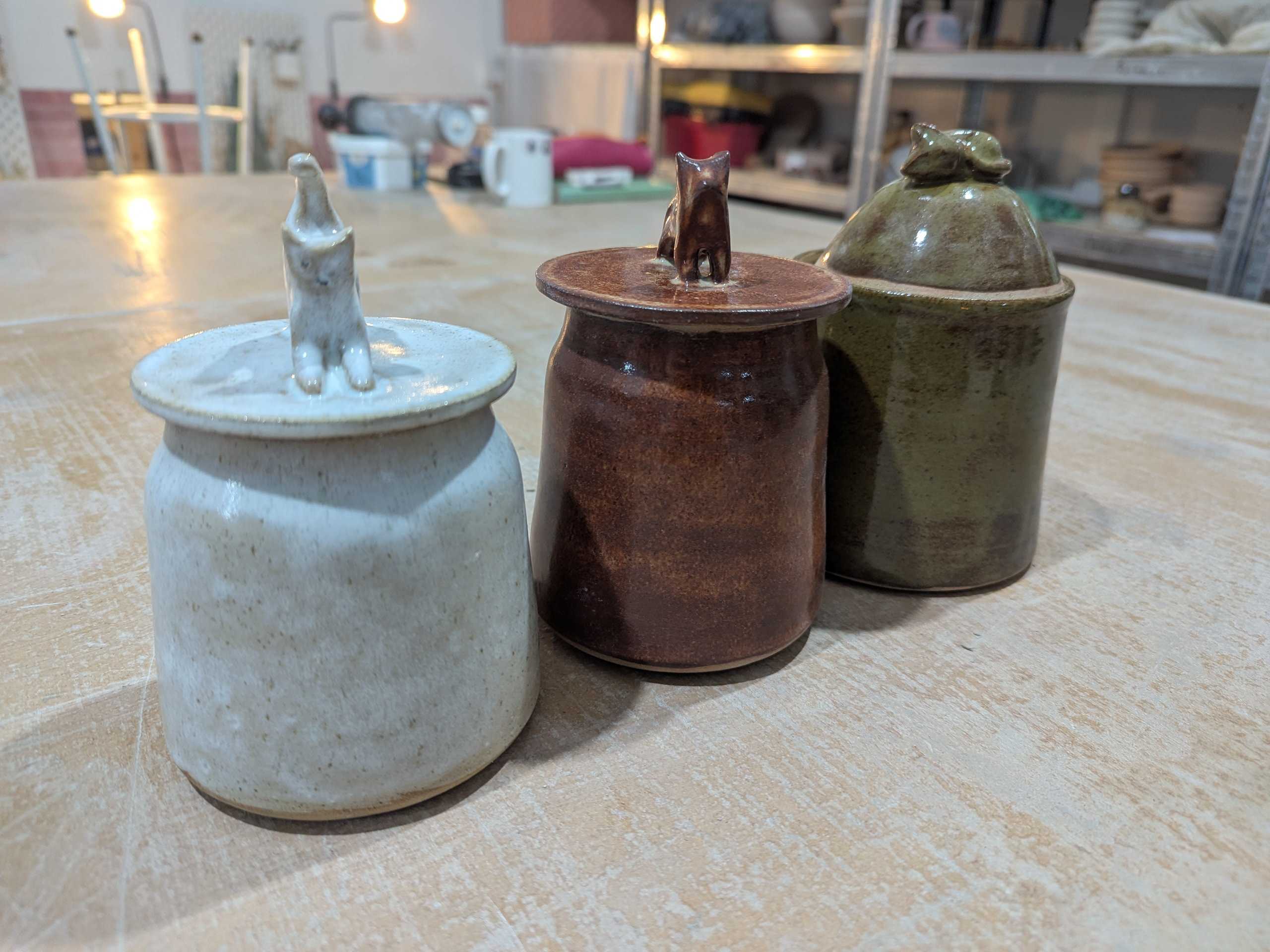 Three lidded jars topped with small animal figures